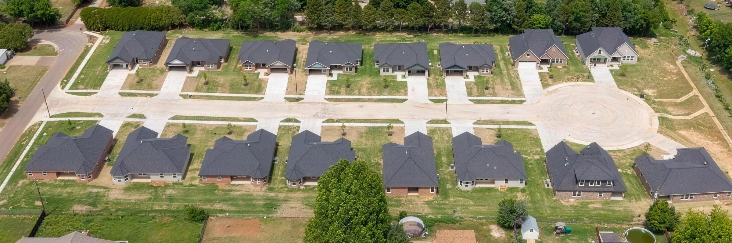Aerial photograph of Meadow Hills Estates on E Abbot Lane — all sixteen new-construction homes lining both sides of the street, with the cul-de-sac at the east end